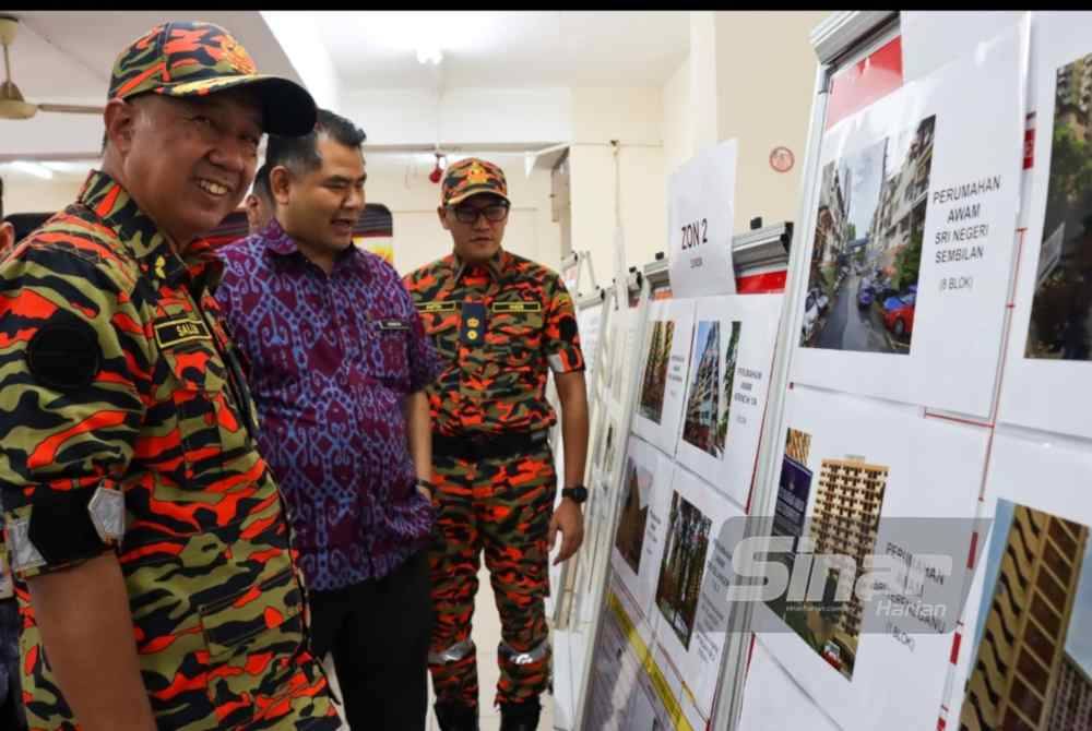 Muhammad Salleh (kiri) melihat gambar perumahan awam yang terlibat dalam pemeriksaan keselamatan kebakaran.