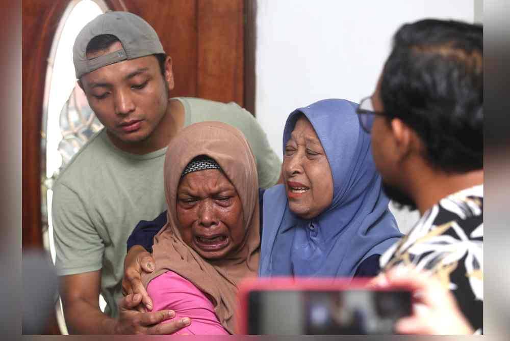 Syazwan (kiri) menenangkan ibunya yang tidak dapat menahan sebak mengenangkan kejadian menimpa Allahyarham