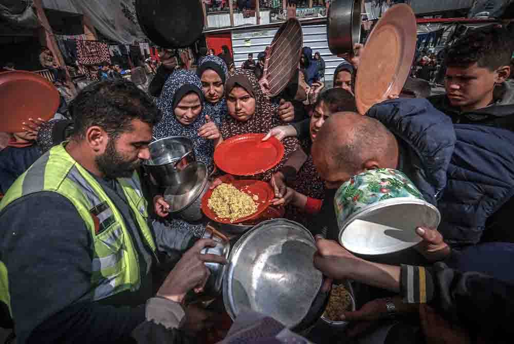 Seorang sukarelawan mengagihkan makanan kepada penduduk Palestin di sebuah sekolah kerajaan di Rafah.