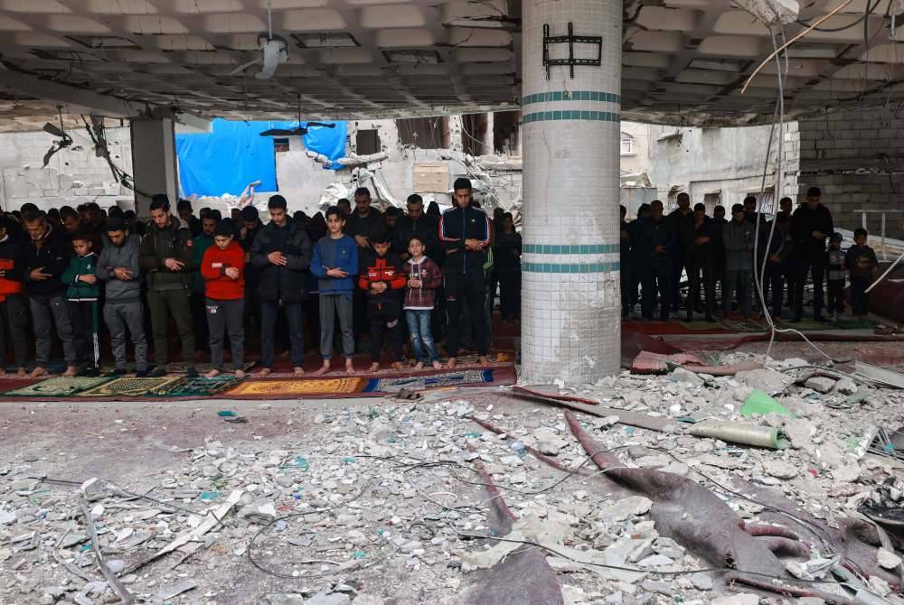 Penduduk Palestin menunaikan solat Jumaat di Masjid al-Hoda di Rafah yang separa musnah dibedil Israel pada pertengahan bulan lalu. Foto AFP