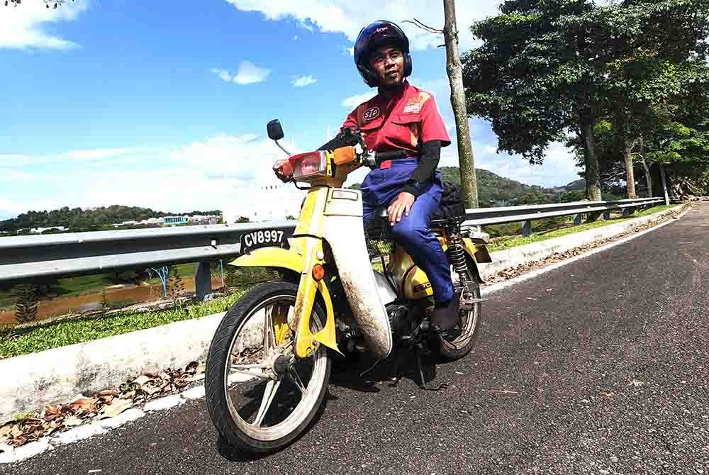 Mat Dam menunggang motosikal dengan menggunakan satu tangan tangan kiri Mat Dam yang terkulai selepas lumpuh akibat terbabit dalam kemalangan jalan raya.