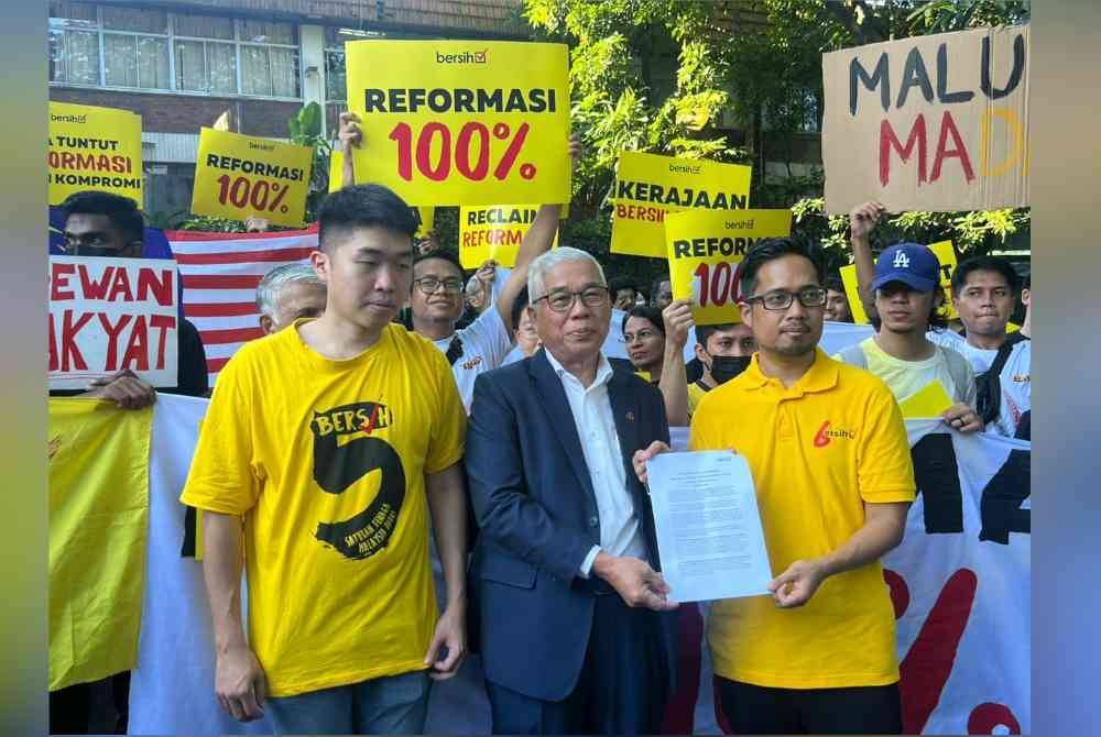 Hassan (tengah) menerima memorandum daripada Muhammad Faisal ketika perhimpunan #Reformasi 100 peratus pada Selasa.