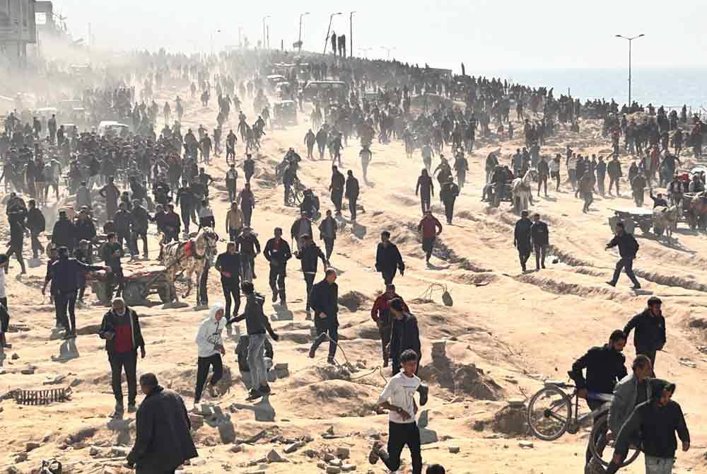 Penduduk Palestin menunggu bantuan kemanusiaan di tepi pantai di Bandar Gaza, Semenanjung Gaza - Foto AP