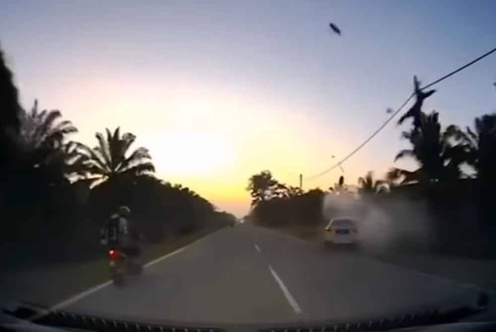 Tangkap layar video kejadian menunjukkan penunggang motosikal melambung tinggi selepas dirempuh sebuah kereta ketika memotong kenderaan lain di Batu 21, Jalan Muar- Parit Sulong, pada Selasa.