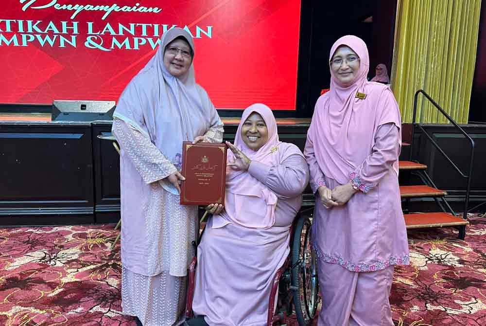 Rohani (kiri) menyampaikan watikah kepada atlet angkat berat paralimpik, Sharifah Raudzah Syed Akil (tengah).