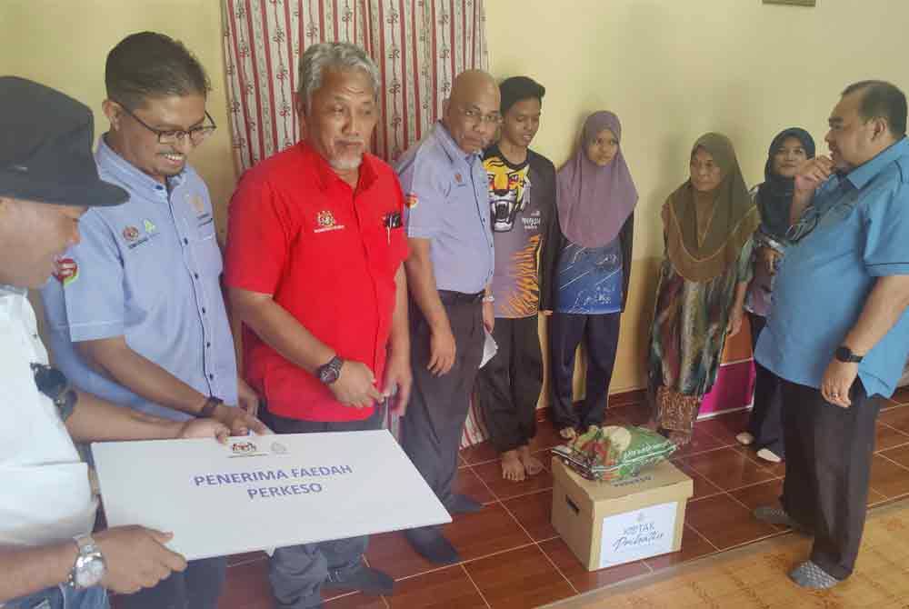 Setiausaha Politik Menteri Kesihatan, Mohammad Faisal Ismail (kanan) dan Ismail (empat dari kiri) serta kakitangan menyerahkan faedah PERKESO kepada waris penerima di Kampung Bukit Badong di sini pada Khamis.