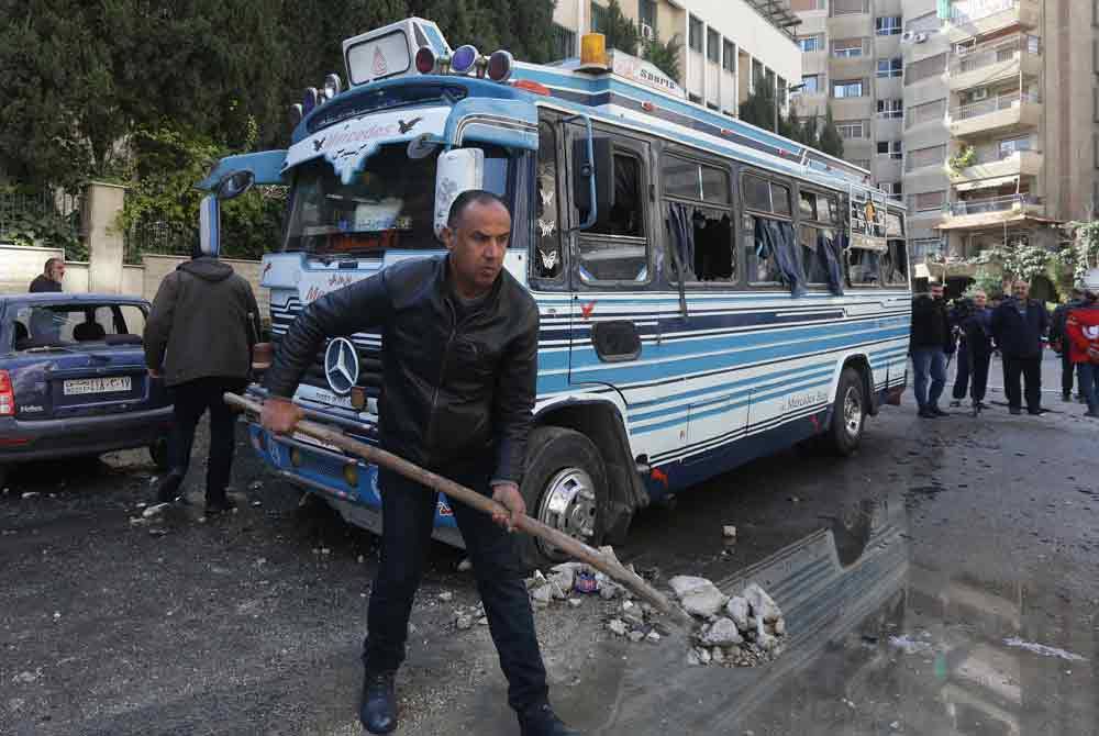 Seorang lelaki membersihkan serpihan akibat serangan udara Israel di daerah Kafr Sousa, Damsyik. - AFP