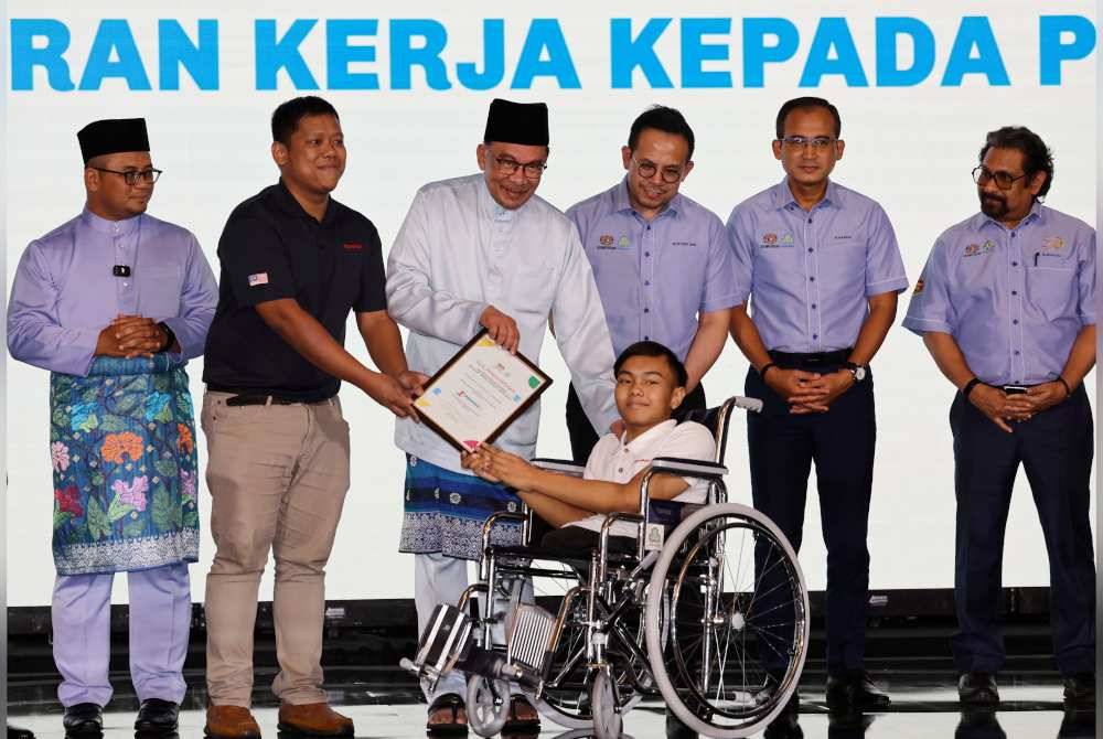 Anwar (tiga dari kiri) menyampaikan sijil penghargaan majikan Kesuma Madani kategori OKU kepada pekerja ExxonMobil Malaysia, Muhammad Izwan Md Said pada Karnival Kerjaya Myfuture Jobs Kesuma Madani OKU dan TVET serta pelancaran Insentif Skim Sokongan Pekerjaan 2024 di IDCC Ideal Convention Centre, pada Jumaat, Turut hadir, Steven (tiga dari kanan) dan Menteri Besar Selangor, Datuk Seri Amirudin Shari (kiri). Foto Bernama