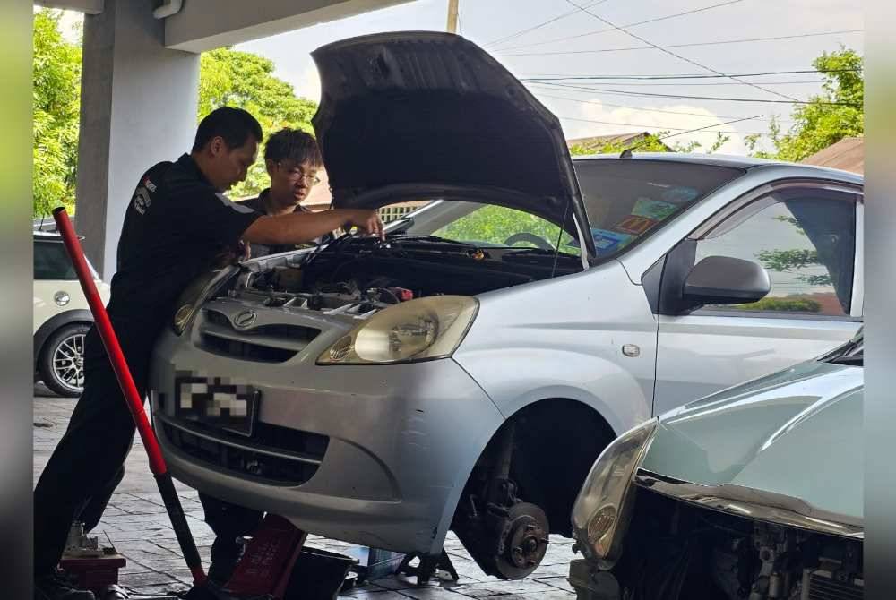 Desmond (kiri) melayan pelanggan yang datang ke bengkelnya pada Jumaat.