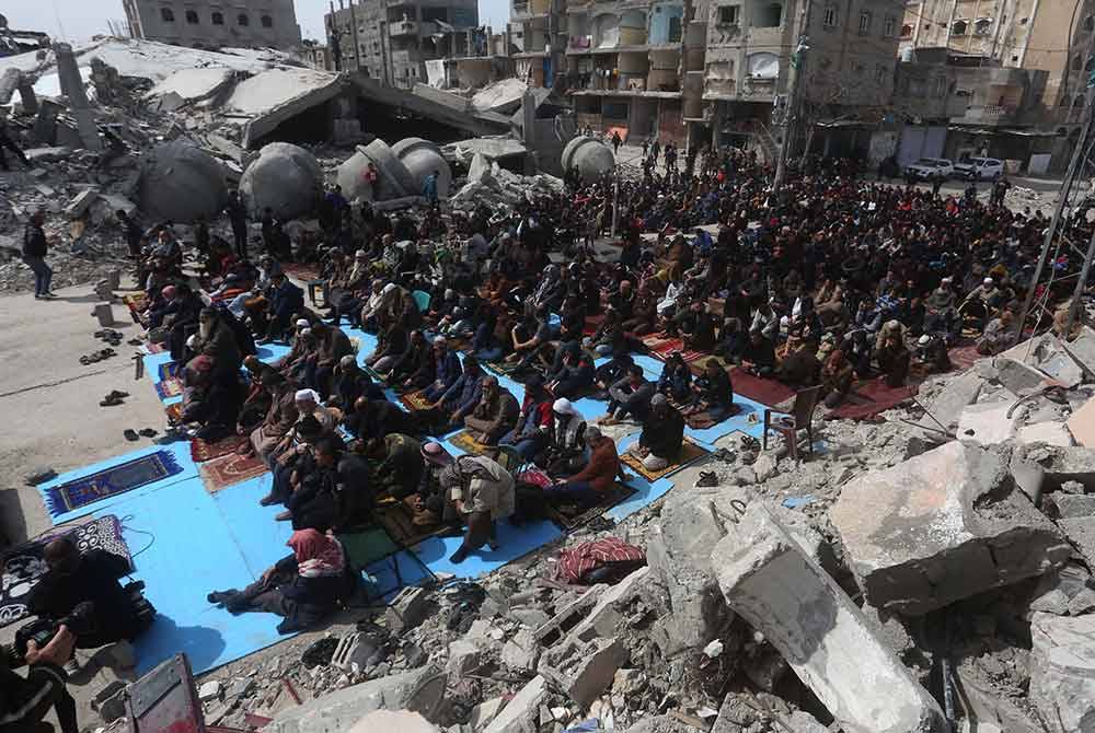 Penduduk Palestin menunaikan solat Jumaat berhampiran masjid yang musnah dalam serangan Israel, di bandar Rafah di selatan Semenanjung Gaza. - Xinhua