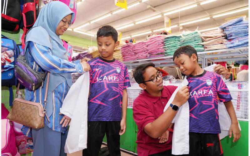 Lokman Al Hakim dua dari kanan) mencuba baju sekolah pada salah seorang anaknya di Pusat Pakaian Hari-Hari, Seksyen 18, Shah Alam.