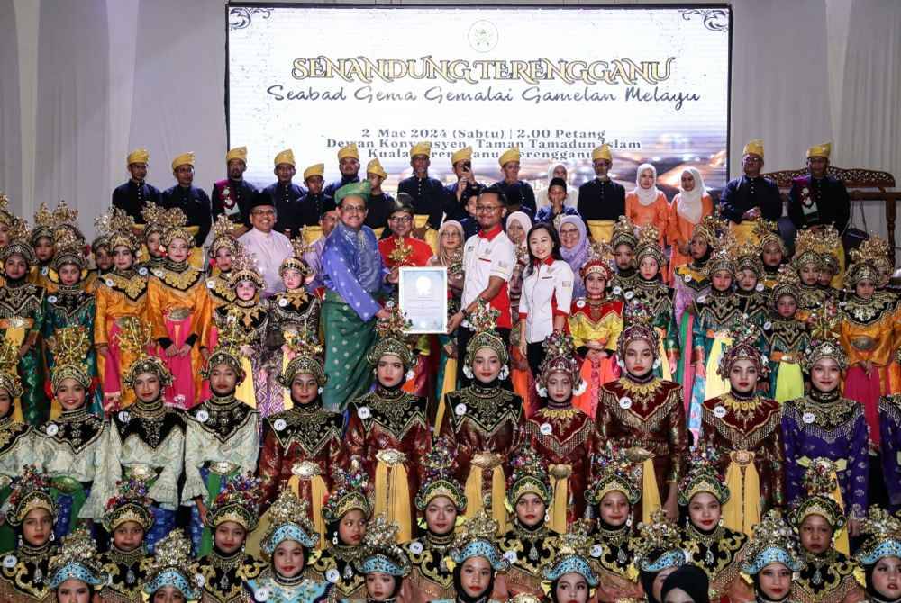 Ahmad Ridzwan (baju biru) menerima sijil Anugerah Malaysia Book of Records (MBOR) dari wakil MBOR Nazrul Hafizi (tengah) pada Majlis Minum Petang Se-Abad Gema Gemalai Gamelan Melayu-Senandung Terengganu di Dewan Konvensyen Taman Tamadun Islam hari ini. Foto Bernama