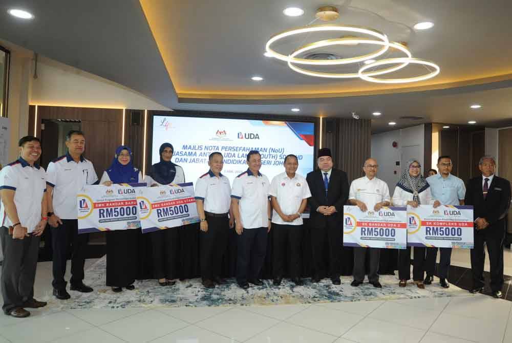 Aznan Tamin (enam dari kanan) bergambar bersama penerima geran Program Pendidikan Kelestarian pada Majlis Nota Persefahaman (NoU) Kerjasama Antara Uda Land (South) Sdn Bhd dan Jabatan Pendidikan Negeri Johor di Wisma SBBU, Johor Bahru.