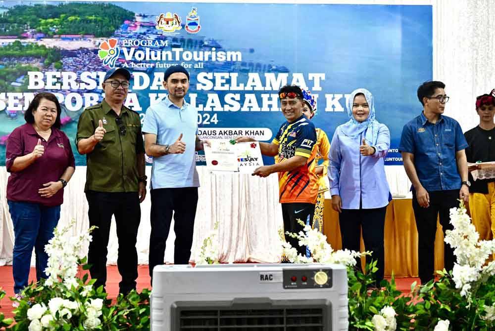 Khairul Firdaus (tiga dari kiri) menyampaikan sijil kepada salah seorang peserta Program Voluntourism: Bersih dan Selamat Semporna Kalasahan Ku. Foto Facebook MOTAC