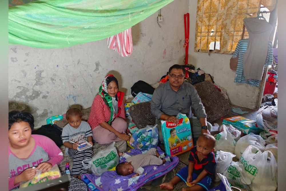 Suahana (tengah) bersama Nur Alisha Umairah (kiri) dan anak-anaknya selepas menerima sumbangan disampaikan Mas Imran (kanan) di rumahnya di Taman Sinaran, Kempas, Johor Bahru pada Rabu.