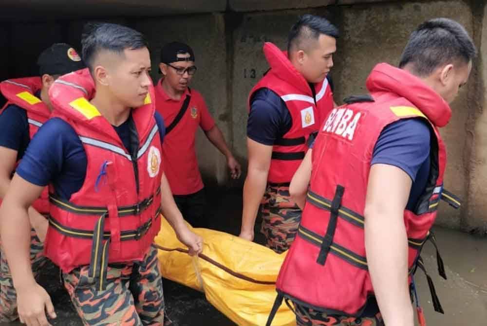 Anggota bomba mengangkat mayat remaja OKU yang ditemui lemas ketika bermain air longkang di Jalan Rajawali 16, Taman Wawasan, Kulai. - Foto BBP Kulai