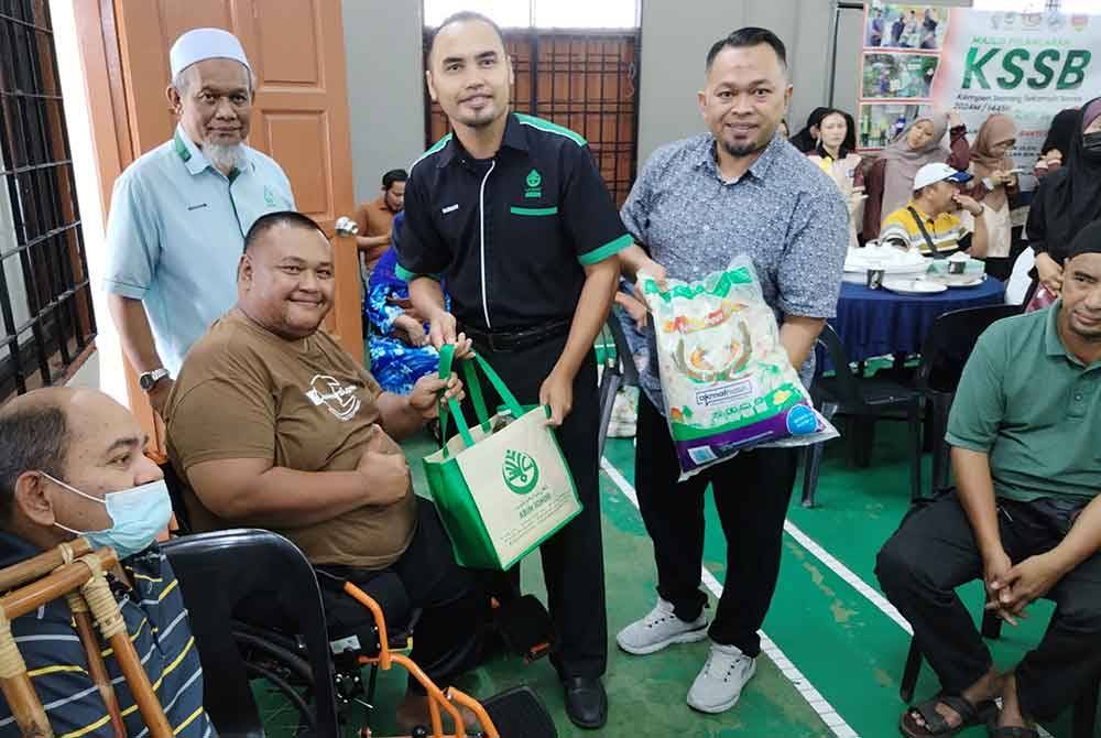 Farhan (berdiri, dua kanna), menyampaikan sumbangan kepada penerima sempena pelancaran program KSSB di Dewan Kampung Melayu Majidee, pada Jumaat.