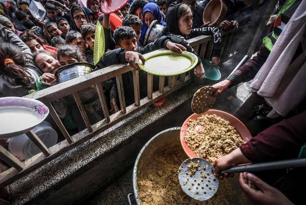 Kanak-kanak Palestin yang dipindahkan berkumpul untuk menerima makanan di sebuah sekolah kerajaan di Rafah di selatan Semenanjung Gaza.