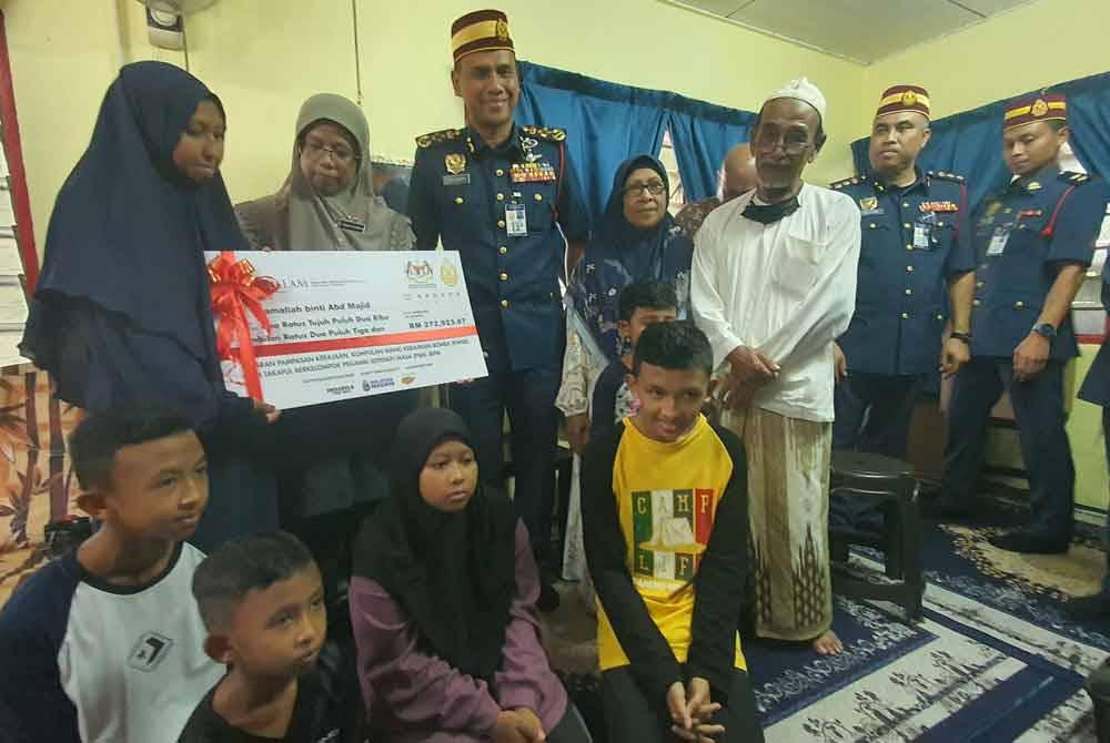 Aiman Athirah menyampaikan replika cek bayaran pampasan dan faedah takaful kepada isteri allahyarham Mohd Izwan, Jamaliah di Pekan Darat, Butterworth pada Jumaat.