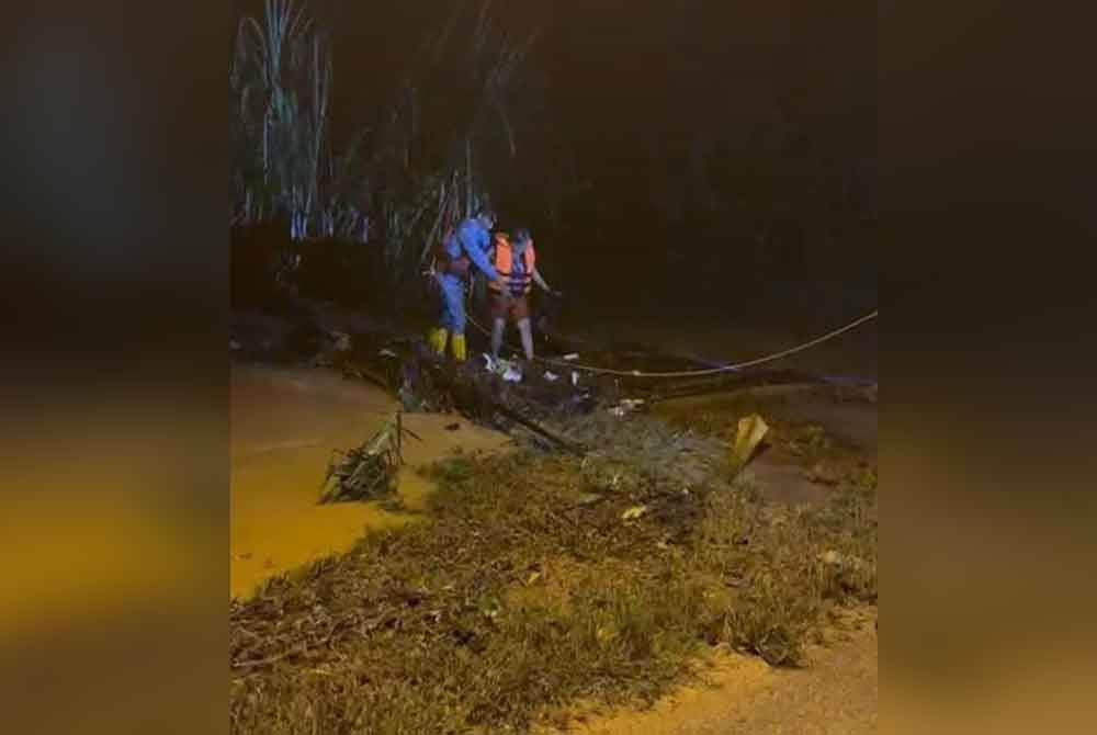 Anggota APM Port Dickson membantu seorang wanita warga emas yang terperangkap di kebunnya akibat banjir kilat di Kampung Baru Tanah Site C, Chuah, Port Dickson pada Jumaat. Foto ihsan APM