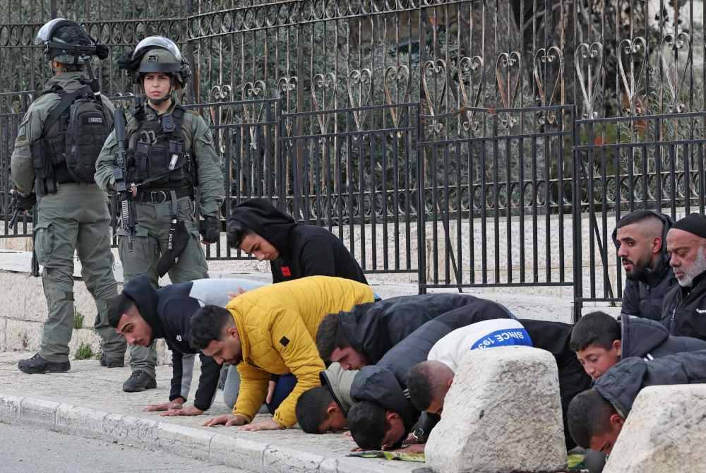 Anggota tentera Israel berjaga-jaga ketika umat Islam Palestin menunaikan solat Jumaat Zohor di sebuah jalan di timur Baitulmaqdis. Foto AFP