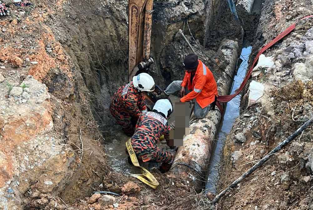 Anggota bomba mengeluarkan mangsa yang setelah ditimbus runtuhan tanah di Jalan Renggam- Bukit Benut di sini, pada petang Sabtu. - Foto Bomba