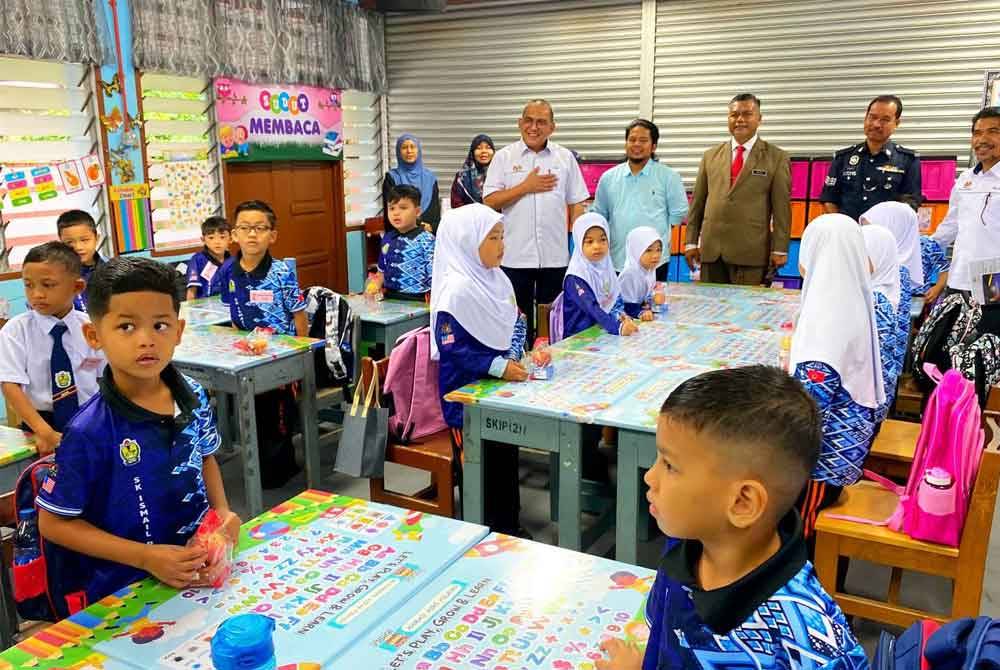 Mohd Zamri (kiri) meninjau murid darjah satu di SK Ismail Petra 1, Kota Bharu pada Ahad.