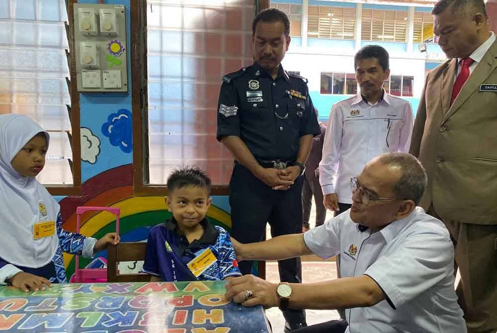 Mohd Zamri (duduk) beramah mesra dengan murid darjah satu di SK Ismail Petra 1, Kota Bharu pada Ahad.