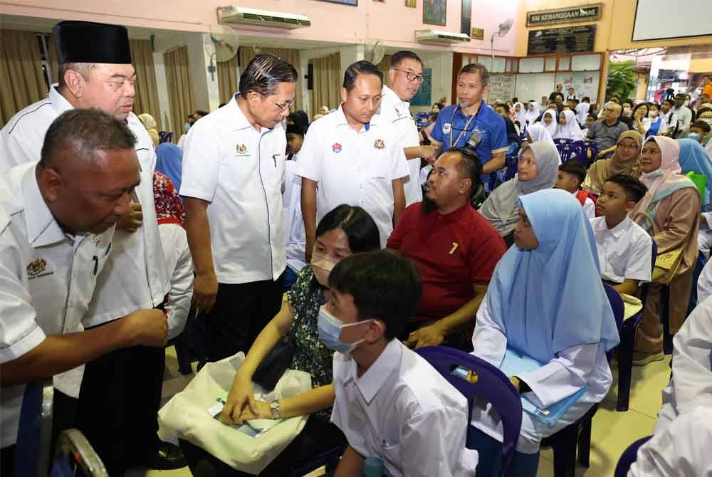 Azman (tiga dari kiri) dan Aznan (empat dari kiri) beramah mesra dengan ibu bapa dan pelajar pada hari pertama pembukaan sekolah sesi akademik 2024/2025 di Sekolah Menengah Kebangsaan Sultan Ismail hari ini. Foto Bernama