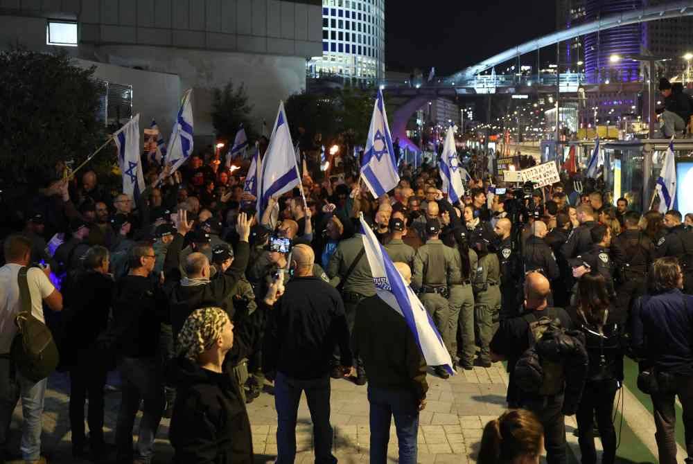 Anggota keselamatan Israel mengawal aktivis anti-kerajaan dan penunjuk perasaan yang berhimpun bagi mendesak pembebasan segera tebusan yang diculik Hamas dan peletakan jawatan Perdana Menteri Israel, Benjamin Netanyahu di Tel Aviv. Foto AFP