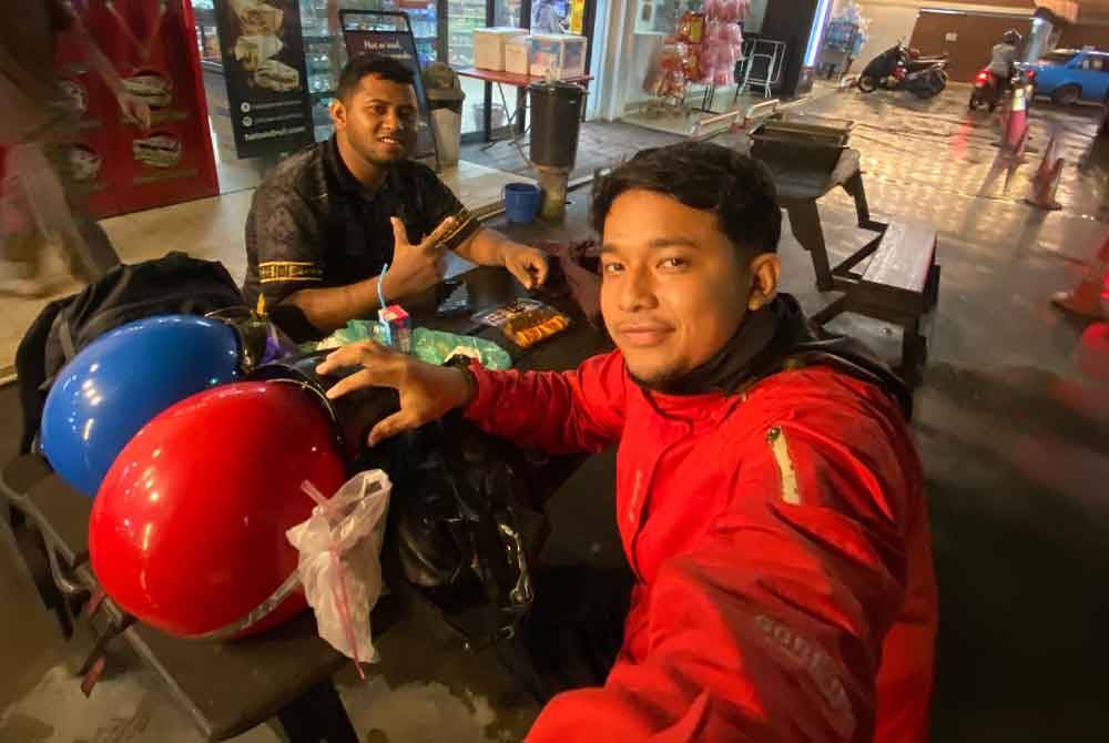 Mohamad Hafiz bersama rakan, Alif Haikal berehat sebentar selepas mengisi minyak petrol di petrol pam.