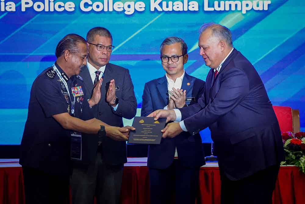 Razarudin (kiri) bersama Pengerusi MCMC, Tan Sri Mohamad Salim Fateh Din (kanan) bertukar memorandum perjanjian persefahaman antara PDRM dengan MCMC sambil diperhatikan Saifuddin Nasution (dua dari kiri) dan Fahmi (dua dari kanan) pada Majlis PDRM Special Dialogue 2024 di Maktab PDRM pada Isnin. Foto Bernama