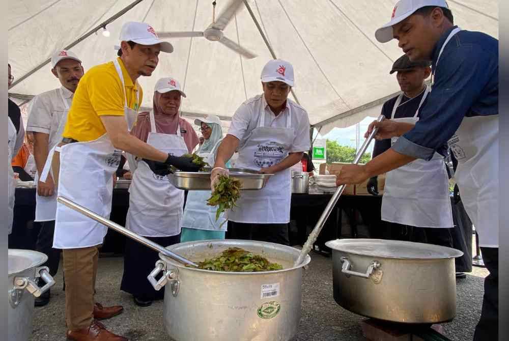 Dr Zaini (tengah) turut sama bergotong-royong menyiapkan bubur lambuk semasa program tanggungjawab korporat (CSR) bubuk lambuk semarak Ramadan 2024 kolaborasi bersama Ibis Styles Kota Bharu dan Bahagian Keselamatan dan Kualiti Makanan JKNK pada Isnin.