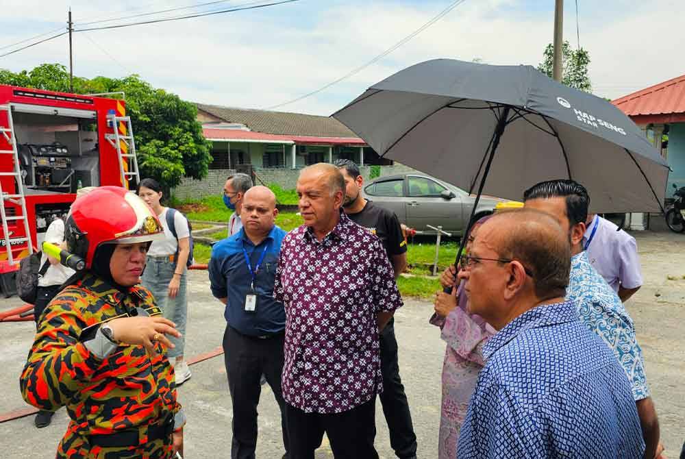 Ameer (tengah) mendengar penerangan daripada Sayani (kiri) berhubung operasi pemadaman yang masih berlangsung di Mydin Manjoi.