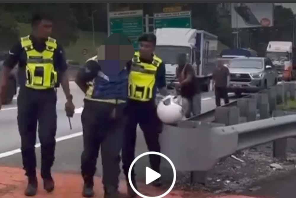 Tangkap layar video tular memaparkan seorang individu berpakaian uniform Polis Diraja Malaysia (PDRM) ditahan dua anggota polis berdekatan Plaza Tol Duta, di sini.