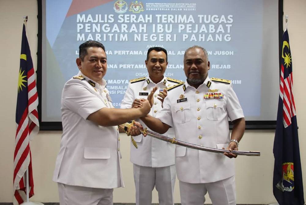 Kamal Ariffin (kanan) menyerahkan pedang
Scimitar kepada Mazlan sebagai simbolik penyerahan tugas
Pengarah Maritim Negeri Pahang baharu di sini pada Selasa.