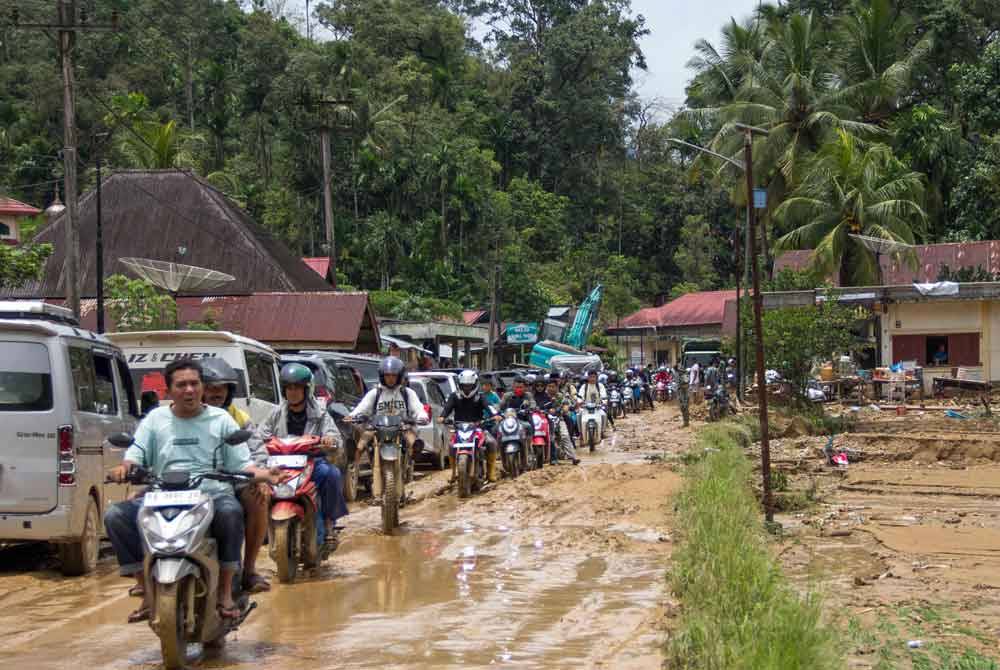 Pengguna kenderaan melalui jalan berlumpur berikutan banjir kilat di Kabupaten Pesisir Selatan, Sumatera Barat, Indonesia pada 9 Mac lalu. Foto AFP