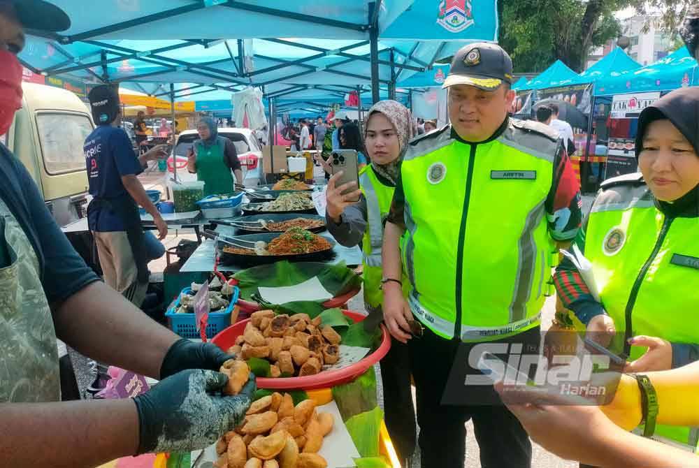 Ariffin (tengah) mendengar penjelasan daripada seorang peniaga. Foto Hisyamuddin Ayub