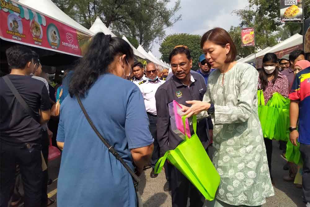 Sandrea (kanan) menyampaikan bekas makanan kepada pengunjung Bazar Ramadan Stadium Perak pada Rabu.