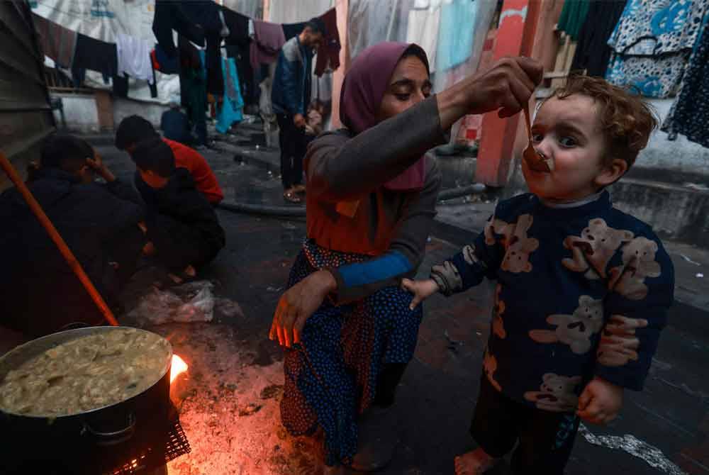 Seorang wanita Palestin menyuapkan makanan kepada anaknya sebelum masuk waktu berbuka puasa pada hari kedua Ramadan di Rafah. Foto AFP