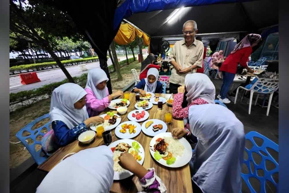 Haziz (berdiri) beramah mesra dengan anak-anak yatim yang diraikan oleh Hotel D&#039;Wharf.