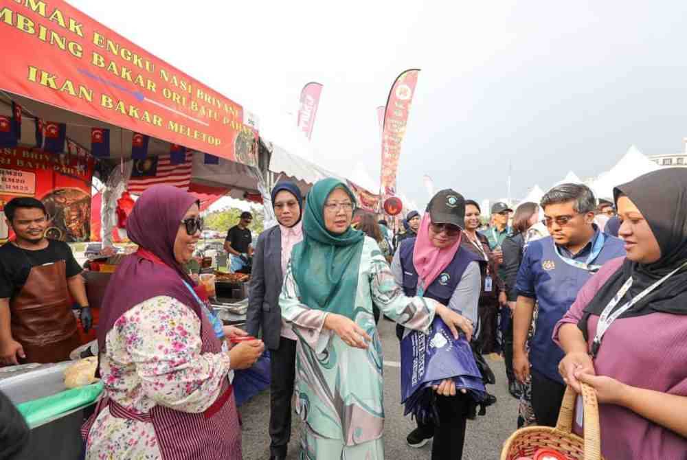 Zaliha menyerahkan beg kepada pengunjung bazar.