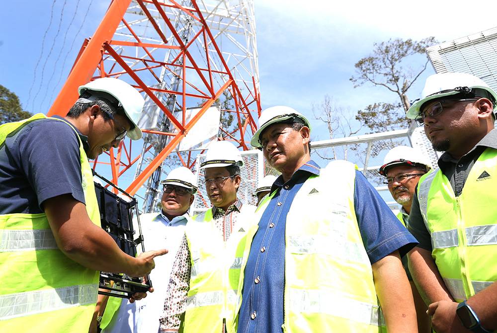 Aminuddin (dua dari kanan) dan Jalaluddin (tiga dari kanan) mendengar penerangan berkenaan projek menara telekomunikasi.