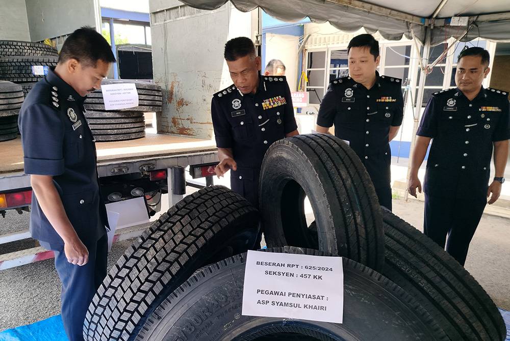 Wan Mohd Zahari (dua dari kiri) menunjukkan sebahagian tayar curi yang dirampas susulan penahanan tiga anggota Geng Vennu pada 4 Mac lalu.