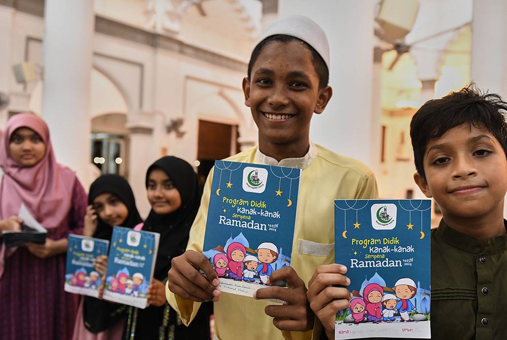 Jemaah cilik menunjukkan buku khas Program Didik Kanak-kanak yang akan dicop dan ditandatangani oleh ahli jawatankuasa masjid setelah selesai mendirikan solat sunat tarawih 23 rakaat di Masjid Kapitan Keling. - Foto Bernama