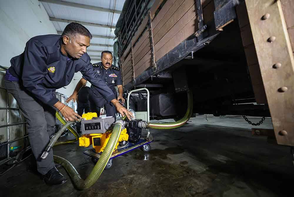 Jegan (kiri) menunjukkan mesin yang digunakan untuk memindahkan bahan api ke IBC Tank. Foto Bernama