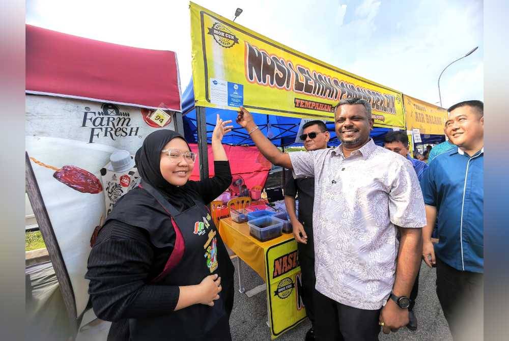 Arul Kumar (dua dari kanan) menunjukkan pelekat tanda sokongan peniaga terhadap program MySaveFood.