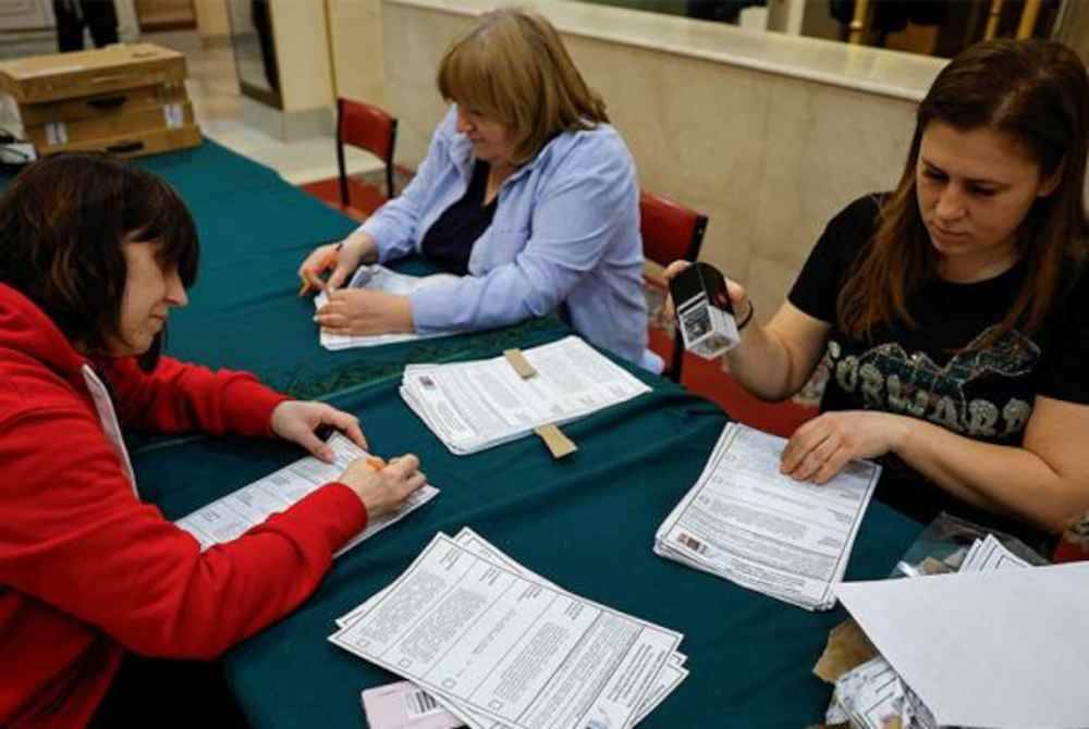 Pekerja Suruhanjaya Pilihan Raya sedang menyiapkan kertas undi di sebuah pusat pengundian Moscow, Rusia. Foto Reuters