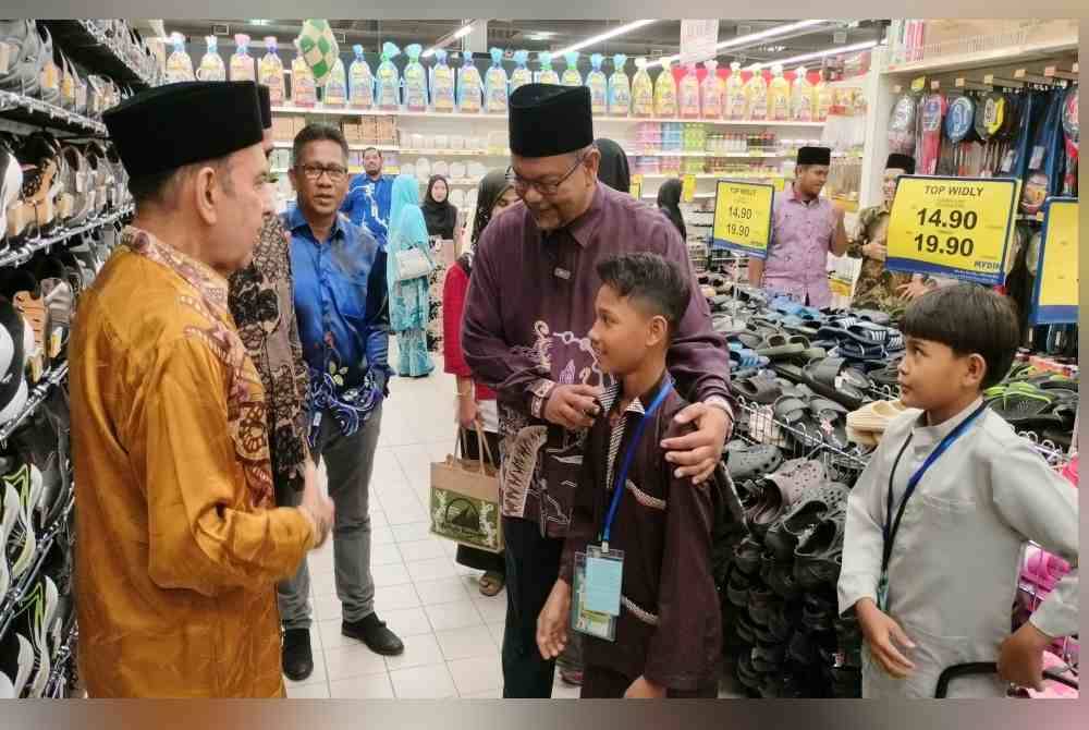 Haim Hilman (kanan) menyantuni anak yatim dan asnaf yang diberi peluang membeli baju raya pada Khamis.