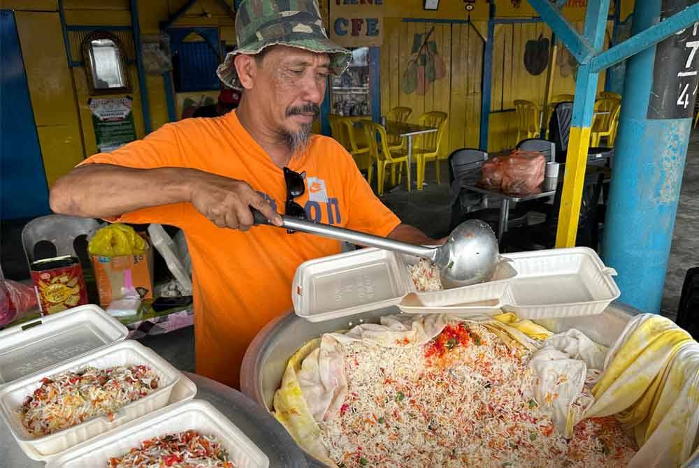 Hasan sedang menyiapkan pesanan pelanggan di bazar Ramadan Pekan Parit Betak, Pontian.